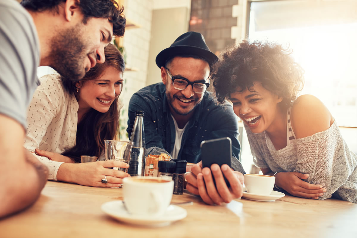 Group of Friends Surrounding Phone at Cafe