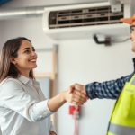 Young woman shaking the hand of HVAC technician.